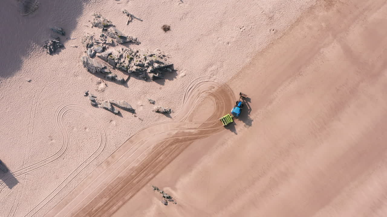 트랙터의 정적 샷 - 북쪽 데본의 모래 해변을 청소하는 트레일러가 돌아서고 있습니다.