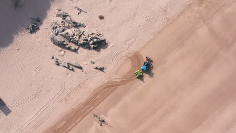 static shot of a tractor - trailer cleaning a sandy beach in north devon turning around