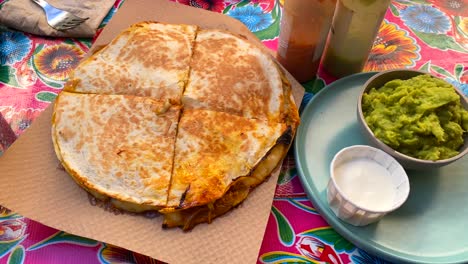 Sabrosa-Quasadilla-De-Pollo-Desmenuzado-Con-Guacamole,-Salsas-Picantes-Y-Crema-Agria-En-Un-Restaurante-Mexicano,-Tortilla-De-Pollo-Picante-Cocida-A-Fuego-Lento-Con-Queso,-Tiro-De-4k