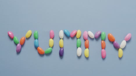 video de vista aérea de un texto delicioso formado por dulces multicolores sobre un fondo azul