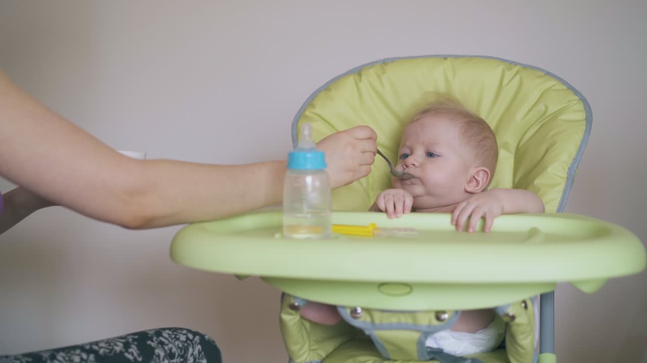 엄마 는 어린 아들이 높은 의자 에 있는 건강 한 식사 를 먹인다
