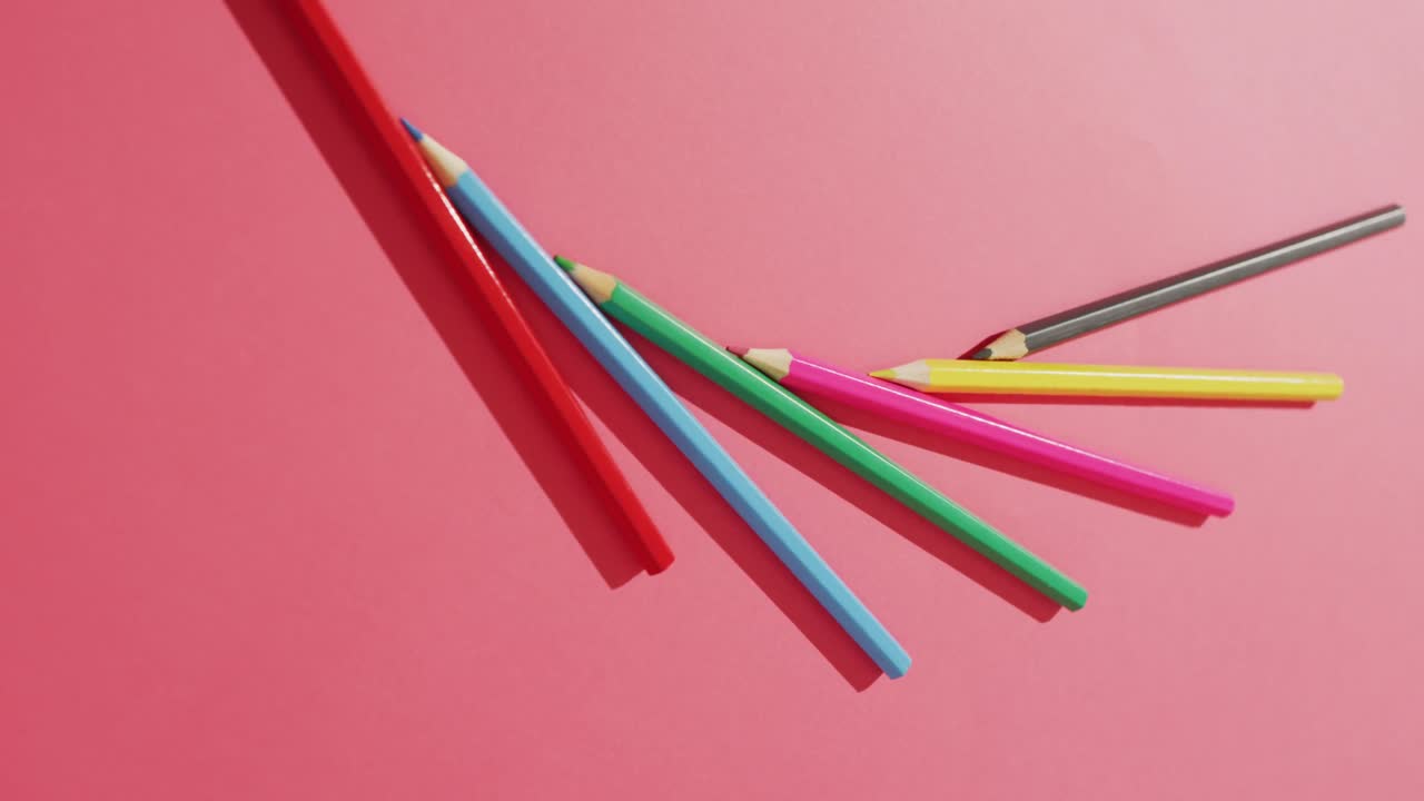 video de composición con lápices de colores en superficie rosa con espacio para copiar