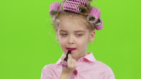 child with lipstick and hair rollers on green screen