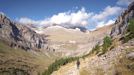 backview of young european man hiker with backpack walking in autumn in ordesa national park, huesca, spain