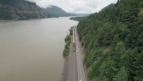 freight train, traffic along columbia river travels towards camera, reverse aerial dolly