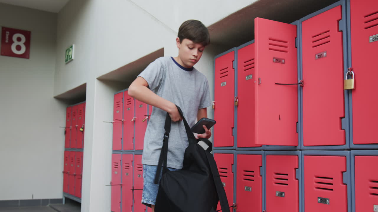 Opening locker, boy in school hallway organizing books and supplies