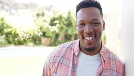 Portrait-of-happy-african-american-man-with-with-short-hair-in-garden-at-home,-slow-motion