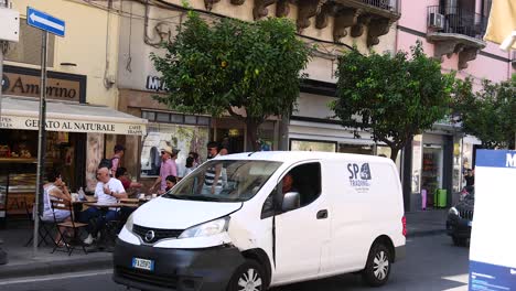 people dining outside, vehicles passing by