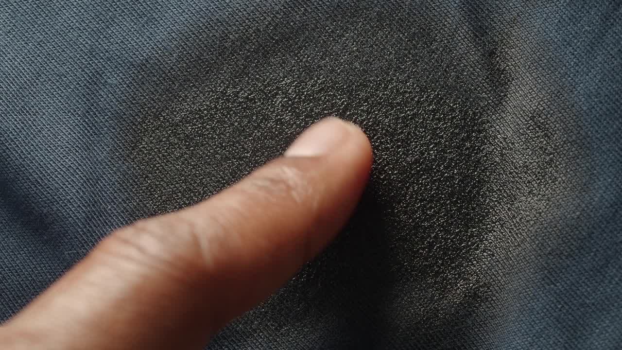 Finger touching a dark textured fabric surface