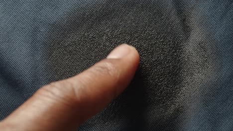 finger touching a dark textured fabric surface