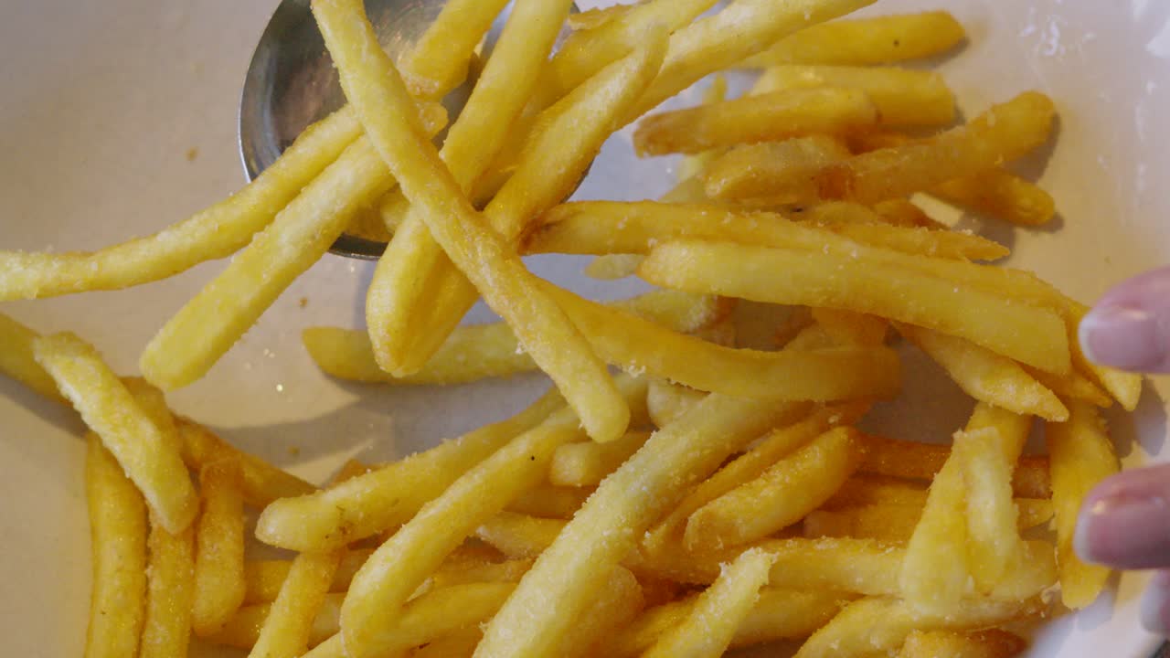 French Fries Chips in Bowl Being Picked Up with Serving Spoon. Unhealthy food. Home Cooking. 4K