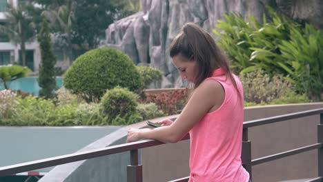 slim-girl-with-smartphone-holds-on-handrail-in-exotic-hotel
