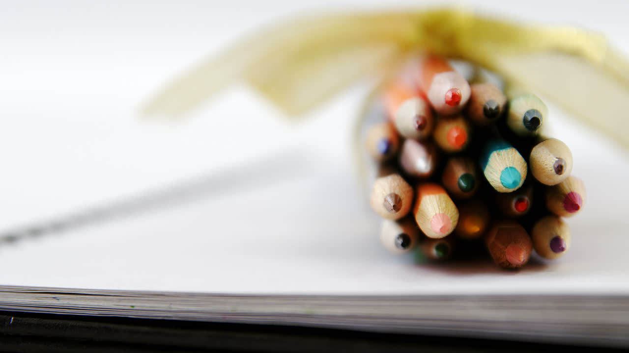 un montón de lápices de color atados con una cinta dorada