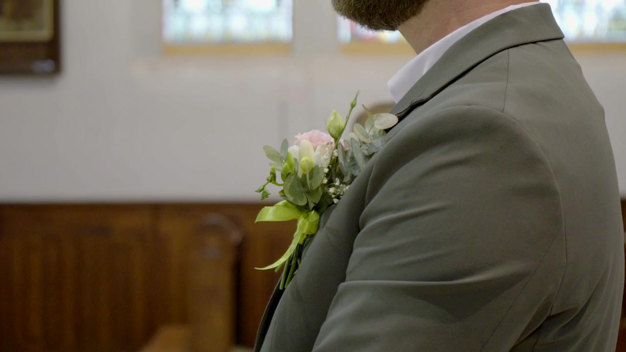Un primo piano della boutonnière dello sposo mentre si trova in chiesa durante la cerimonia nuziale.