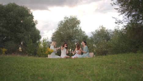 young women in nature in the field in the park together sculpt clay with tools tap clay products with shovels. they communicate share their impressions. general view camera zoom.