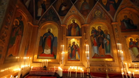 candlelit interior of a church with religious icons and paintings
