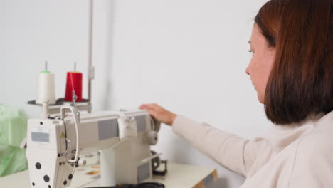 garment maker cutting thread, placing hands on balance wheel rolling mechanical machine, ensuring precise tension, managing speed, focusing on quality sewing, demonstrating professional skill