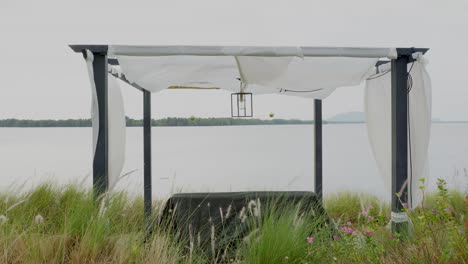 a beautiful riverside pavilion on the bank of the chantaburi river, strong winds causing the white fabric to flutter in the wind as the bad weather has deterred people from relaxing on the loungers