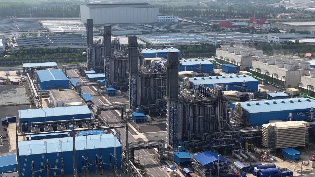 広大な工業地帯に位置する、大規模で近代的なガス火力発電所のハイアングルからの眺め。複雑なパイプライン、タービン、そしてインフラのネットワークを余すところなく映し出しています。