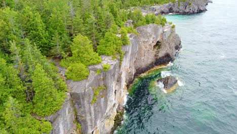 Aerial-steep-rock-off-and-spruce-forest-off-the-Georgian-Bay,-Ontario-in-Canada