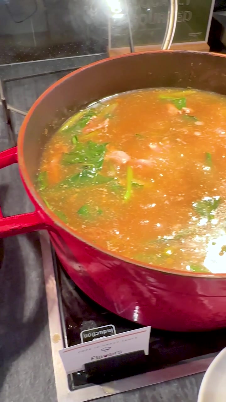 Una telecamera panoramica si sposta da nidi di noodle fritti croccanti a una pentola rossa di zuppa che sobbolle.