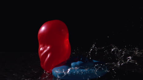 red and blue water balloons falling on black background