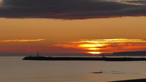 Peaceful-sunrise-over-calm-ocean-and-harbor-sea-wall