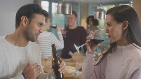 group of multi cultural friends enjoying drinks party with takeaway food at home together