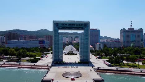 cinematic aerial drone fly through xingfu park arch gate portal with cityscape background