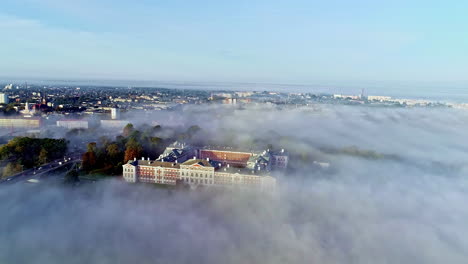 aerial drone shot of thick fog covers the city of jelgava in the morning