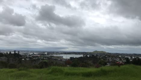 Time-lapse-of-grey-clouds-moving-fast-over-a-grassy-foreground-with-the-cityscape-in-the-background