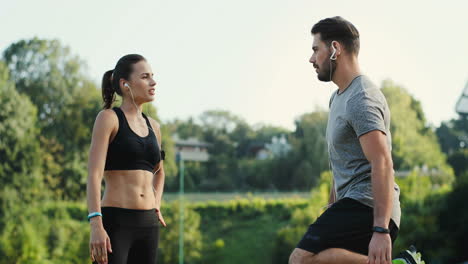 Joven-Pareja-De-Corredores-En-El-Estadio-En-Un-Día-De-Verano-Y-Haciendo-Ejercicio-Para-Manos-Y-Hombros