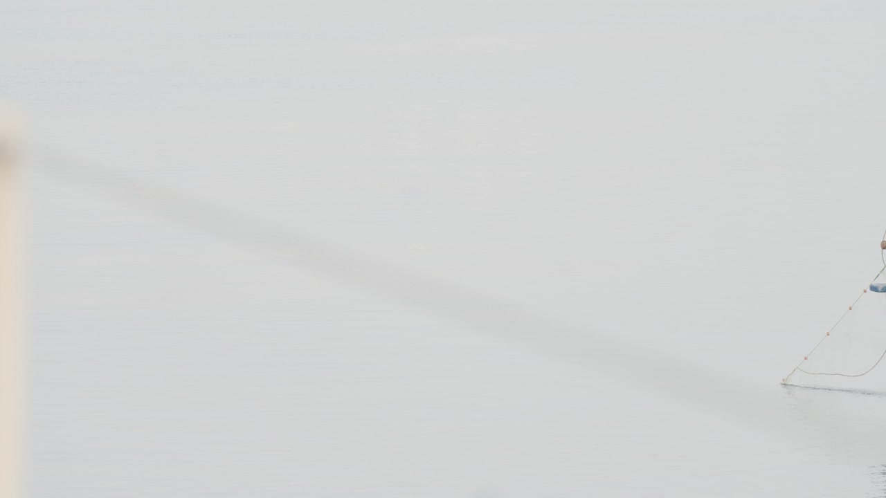 barco pescador recogiendo redes de pesca con una máquina en la parte delantera del barco en mar tranquilo en cámara lenta 60fps