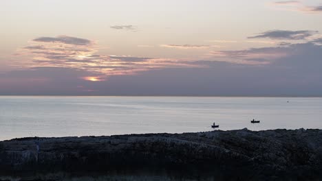 Statische-Aufnahmen-Des-Sonnenaufgangs-über-Dem-Mittelmeer-Mit-Zwei-Fischerbooten,-Die-Sich-Im-Licht-Abheben