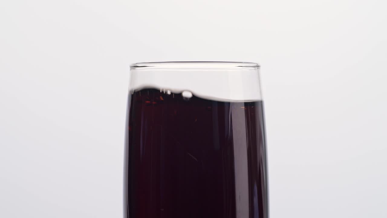 cerca de cubos de hielo cayendo en un vaso de cola fresca sobre un fondo blanco