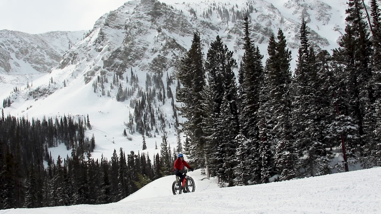 Fat biking up hill in the mountains on the snow