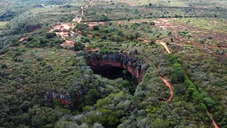 aerial drone dolly in wide shot of the large lapa doce cave entrance of colorful rocks with a self-contained rainforest below in the chapada diamantina national park in bahia, northeastern brazil