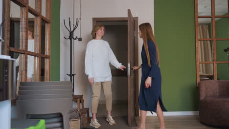 wellness expert walks to wooden door to welcome patient entering room, removing shoes near doorway, in peaceful setting with green accent walls, mirrors on both sides, and soft ambient decor