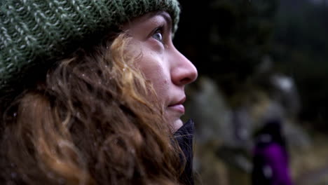 portrait close up young blond hair caucasian woman wearing winter hat during a snow storm, dreamy gaze to the infinite, curios wondering contemplative natural beauty landscape