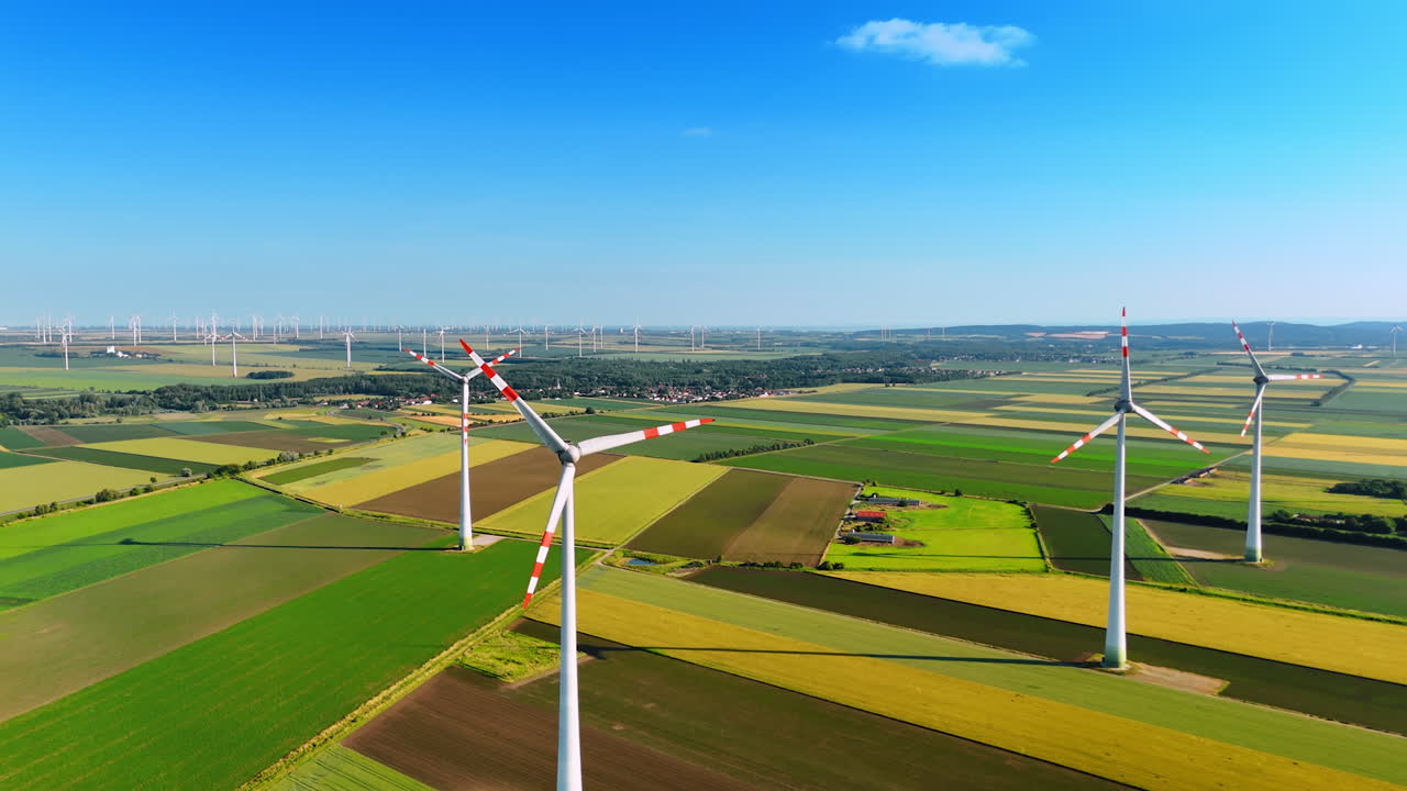 Europe's wind turbines produce energy. Wind turbines stand tall in a vast green landscape, harnessing wind energy under a clear blue sky