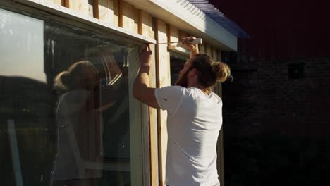 Hombre-Europeo-Midiendo-El-Alféizar-De-La-Ventana-De-Un-Invernadero-En-Un-Día-Soleado-En-Noruega