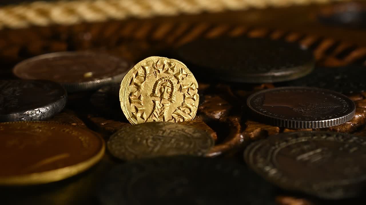 Vecchia moneta d'oro visigota in un vecchio scrigno di legno rotante.