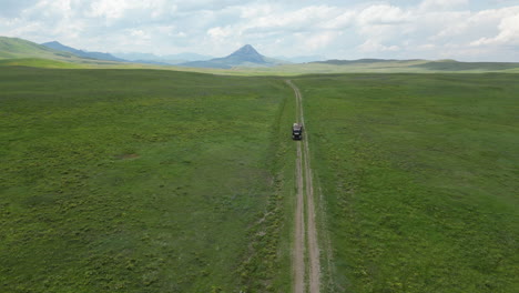 Abandoned-Semi-Truck-Parked-in-the-Middle-of-Car-Trail-in-Vast-Grassy-Valley-Surrounded-by-Mountains