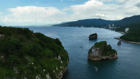 Aerial-view-backwards-over-tour-boats-and-the-Mismaloya-Arches-in-Mexico