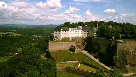 Aerial-footage-of-Drone-flying-backwards-with-monumental-castle-in-sight-until-you-see-the-full-scale-of-the-walls-and-Entrance-in-western-Europe-on-a-partly-cloudy-day