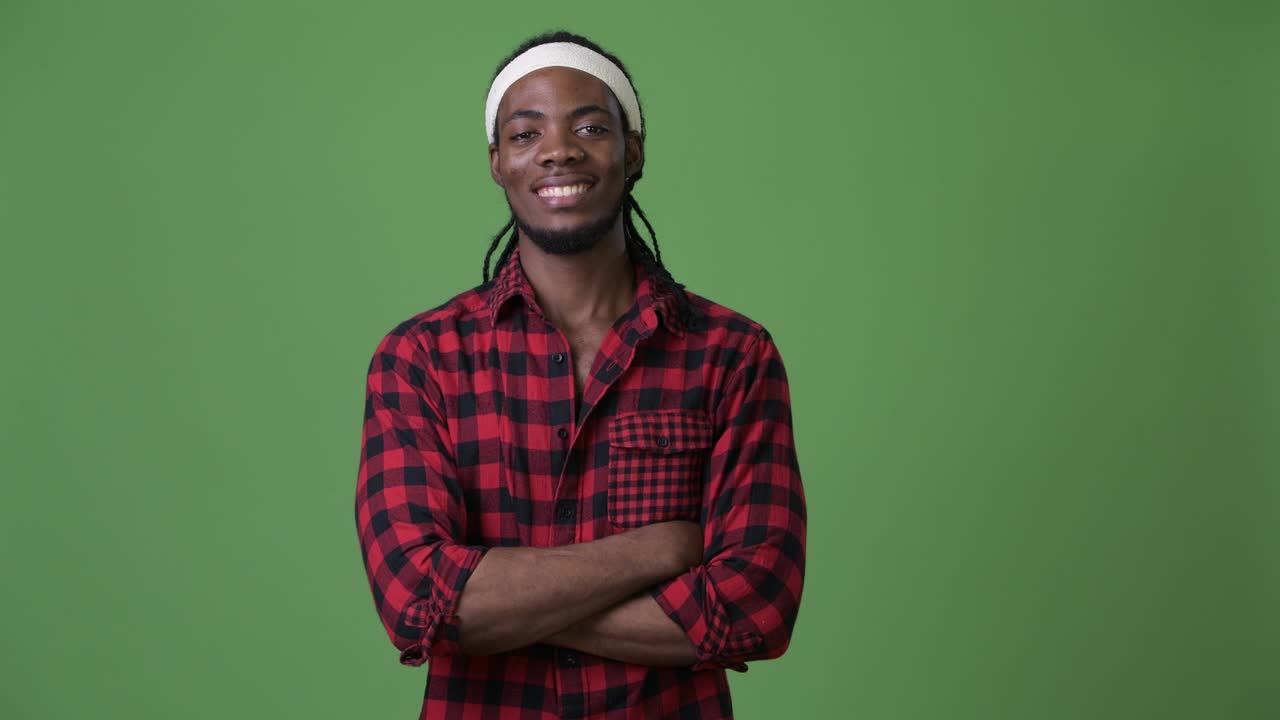 Giovane e affascinante uomo africano con i dreadlock su sfondo verde