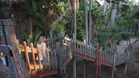 Teenage-Girl-Running-Down-Bridge-in-the-Middle-of-a-Forest-in-White-Sundress-with-Red-Stripes-and-Sandals