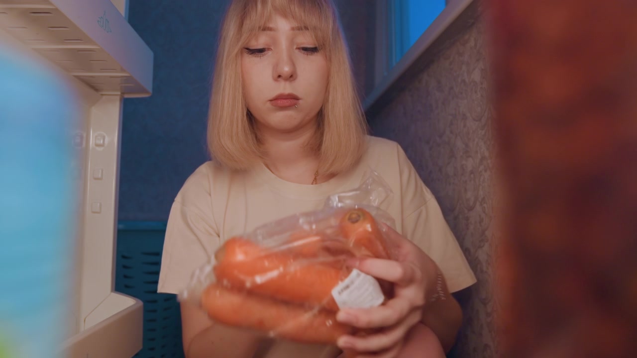 Donna bianca che tiene i pomodori vicino al frigorifero, seleziona prodotti freschi per la preparazione dei pasti, cuoca casalinga informale, mani attente, borsa della spesa, routine in piccola cucina, luce naturale, scelta sana