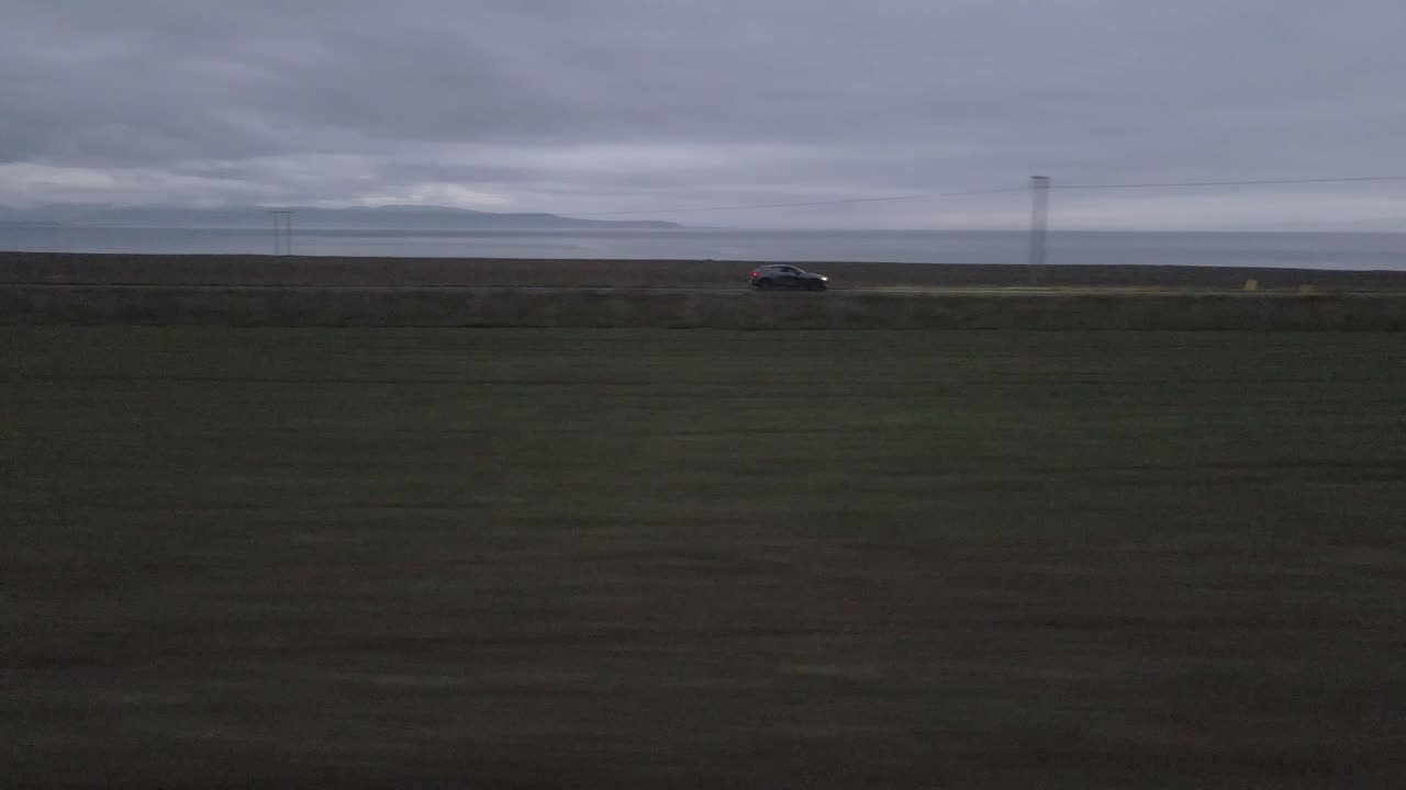 드론은 조용한 저녁을 통해 운전하는 차를 따라, 그 헤드라이트는 어두운 색의 합병을 통해 경로를 잘라