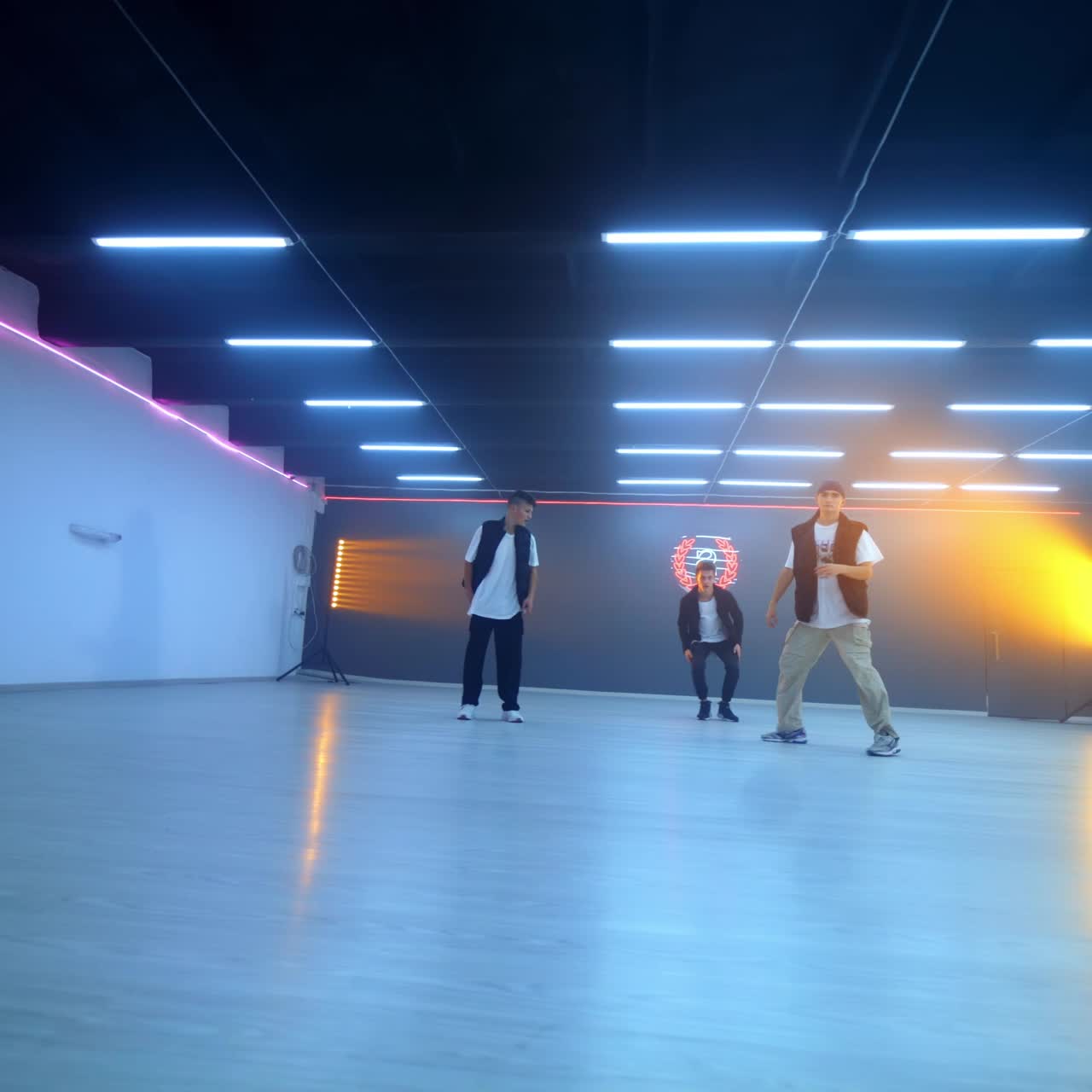 Three male dancers showing a dance in the spacious studio. Boys band dancing hip hop. Low angle view